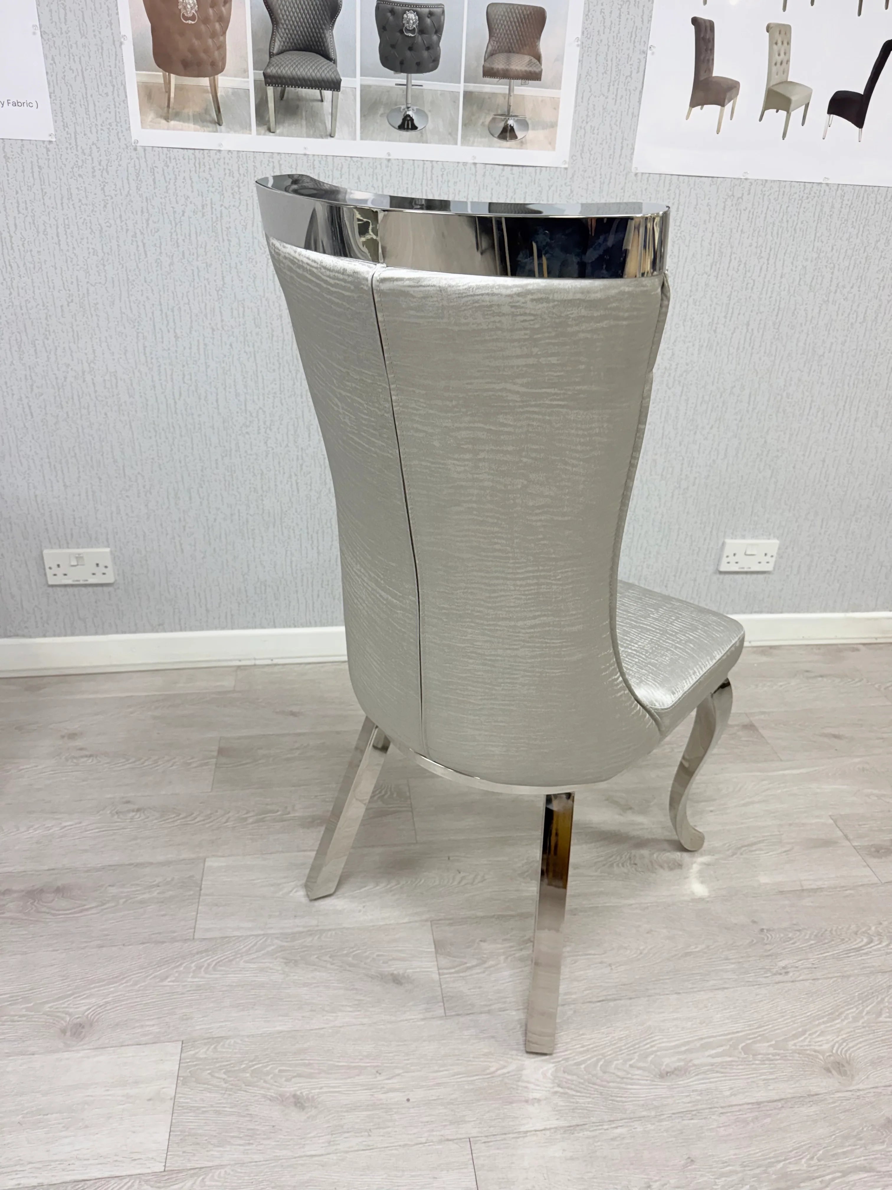 Grey upholstered dining chair shown from the rear highlighting its tall sculpted back design