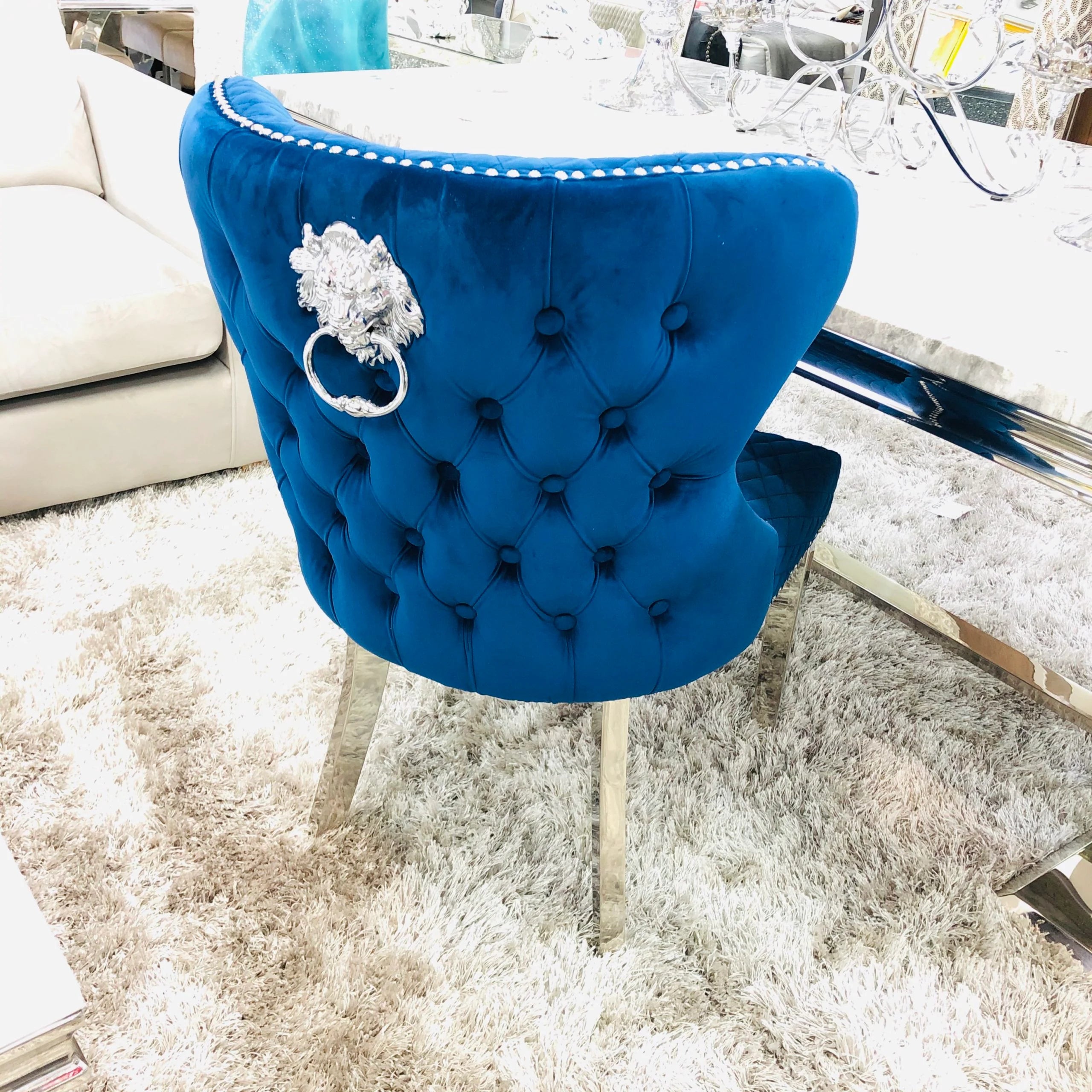 Upholstered navyValentino dining chairs with ornate lion knocker backs for premium dining rooms