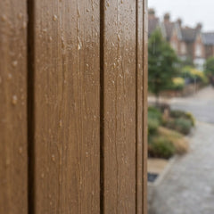 Oak composite cladding panels on a modern exterior during rainy UK weather, demonstrating the weather-resistant properties of outdoor wall panelling.