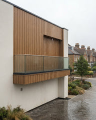 Oak Outdoor Composite Wall Panels shown on an exterior wall during rainy weather, highlighting their weather-resistant outdoor cladding finish.