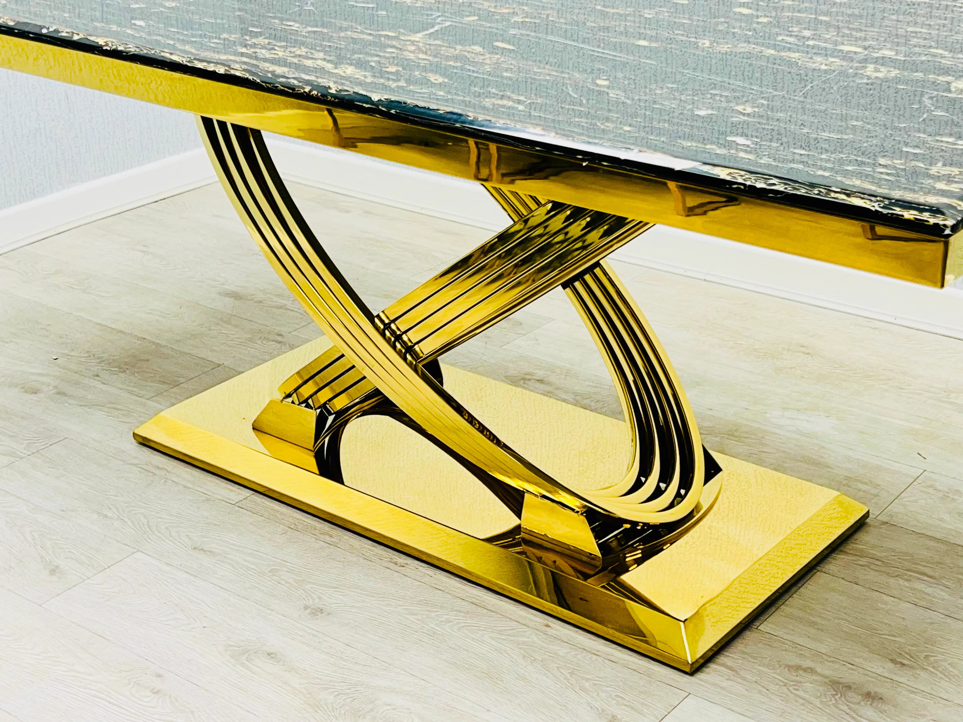 Luxury Ravello black marble dining table featuring a polished stainless steel gold-finish geometric pedestal, perfect for statement contemporary dining rooms.